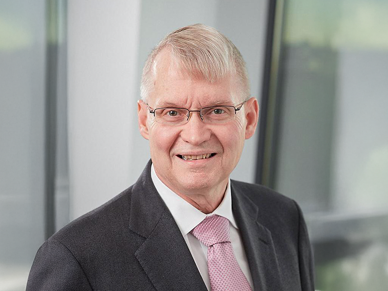 A man in a suit and glasses smiling