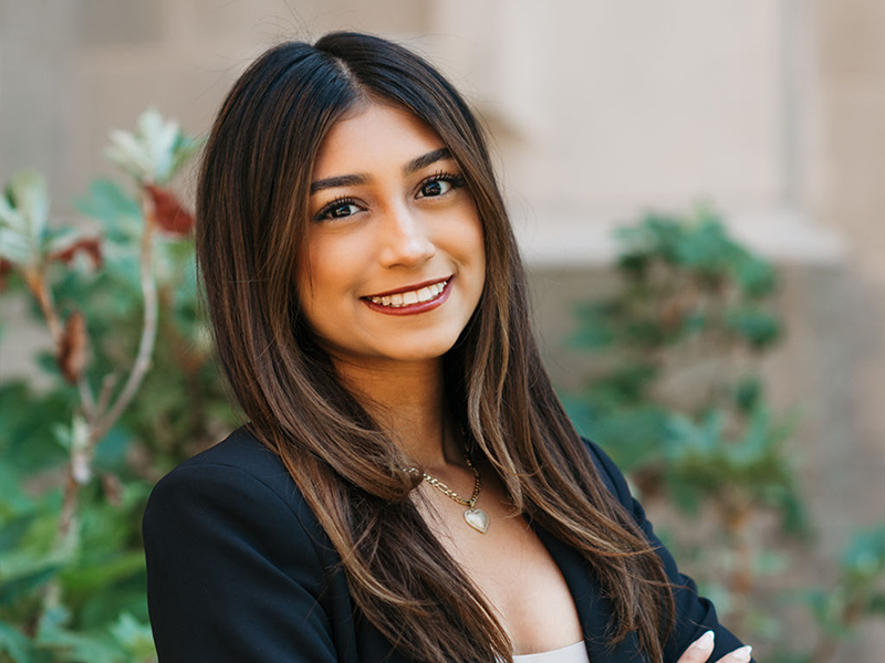 A headshot of a woman wearing a black blazer and silver pendant necklace