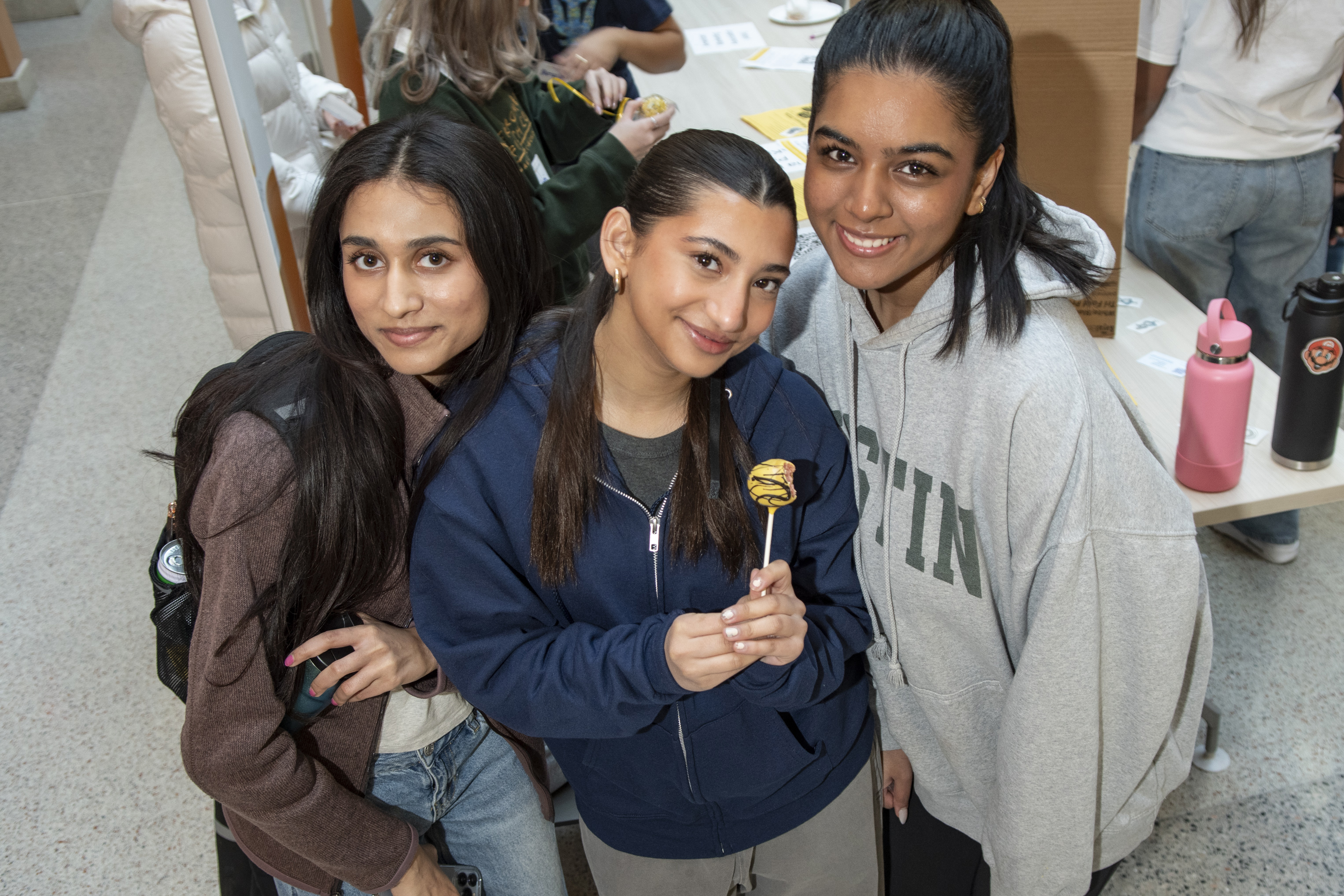 Three students posing with a cake pop