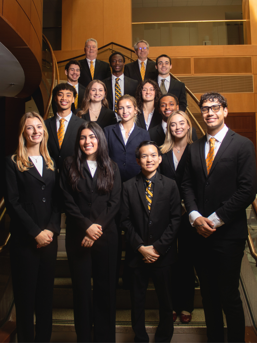 The 2025 VCU Sales Team students and faculty members posing on the Snead Atrium staircase wearing business professional attire.